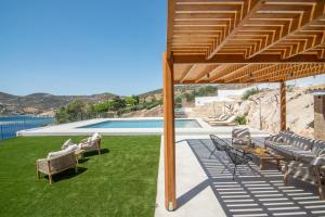 a patio with chairs and a table and a pool at Villa Consta with Tennis, Saltwater Pool & Sea Views by KB Hospitality in Dhaskalión