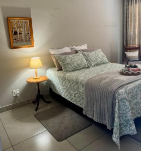 a bedroom with a bed and a table with a lamp at Joba-Rus in Bloemfontein