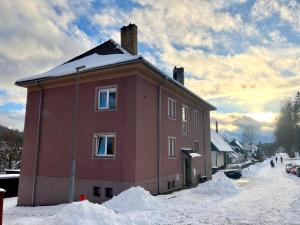 a red house with snow around it on a street at Apartmán U rechlí in Lenora