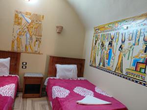 a bedroom with two beds and a painting on the wall at Amon guest house in Abu Simbel +72 photos