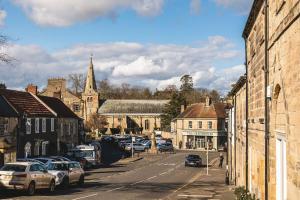 a town with cars parked on a street with a church at Bertram's in Warkworth
