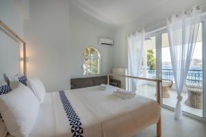 a white bedroom with a large bed and a balcony at Villa Consta with Tennis, Saltwater Pool & Sea Views by KB Hospitality in Dhaskalión