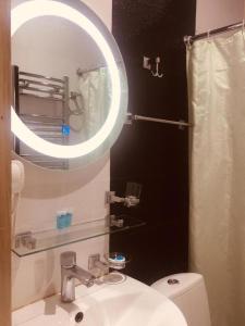 a bathroom with a sink and a mirror and a toilet at Hotel New Royal in Tbilisi City