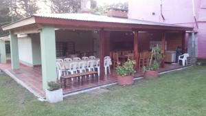 a screened in porch with white chairs and plants at CARELHUE-1 Zarate in Zárate