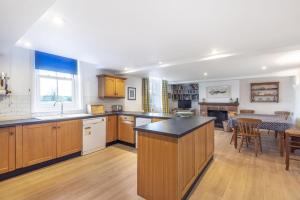 a large kitchen with wooden cabinets and a table at Nelson Lodge in Burnham Market +19 photos
