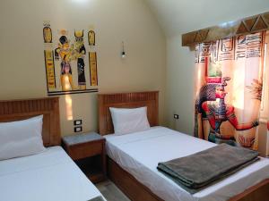 a bedroom with two beds and a painting on the wall at Amon guest house in Abu Simbel