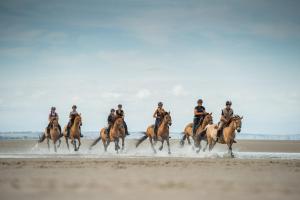 a group of people riding horses on the beach at Escapade aux Peupliers in Vironchaux