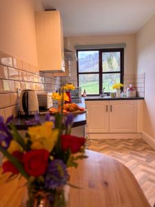 a kitchen with a vase of flowers on a table at Lake Cottages at Cwm Chwefru in Llanafan-fawr