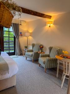 a bedroom with a bed and two chairs and a table at Lake Cottages at Cwm Chwefru in Llanafan-fawr +289 photos