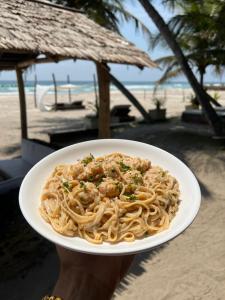 a person holding a plate of pasta on the beach at O'Sole Mio Assinie - La résidence in Assinie