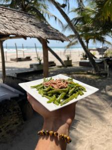 a person holding a plate of food on a beach at O'Sole Mio Assinie - La résidence in Assinie