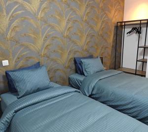 two blue beds in a room with a wallpaper at Au pays des cigognes in Cambron-Casteau