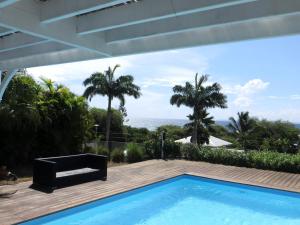 a swimming pool with a view of the ocean from a house at Villa Paradis - vue mer, piscine et jacuzzi in Sainte-Anne