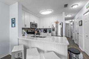 a kitchen with white cabinets and a stainless steel refrigerator at The Dunes 101 by Vacation Homes Collection in Fort Morgan