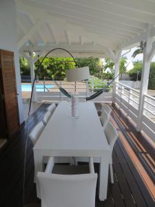 a white table and chairs on a wooden deck at Villa Paradis - vue mer, piscine et jacuzzi in Sainte-Anne