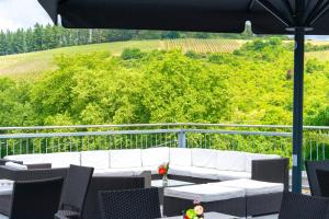 a white couch and chairs on a balcony with a view at Alembra - Wein Style Hotel in Trier
