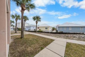 a walkway with palm trees in front of houses at The Dunes 101 by Vacation Homes Collection in Fort Morgan