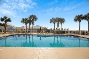 a large swimming pool with palm trees in the background at The Dunes 101 by Vacation Homes Collection in Fort Morgan
