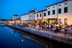 a group of people sitting at tables next to a river at CasaDei Sweet Home Design & Relax - Beach Parking in Cervia