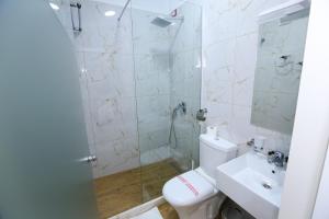 a bathroom with a shower and a toilet and a sink at Hotel Hermes Tirana in Tirana