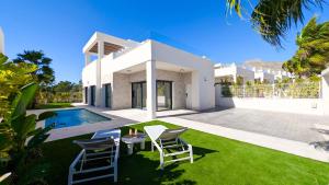 a white house with a yard with chairs and a pool at Villa Horizonte in Finestrat