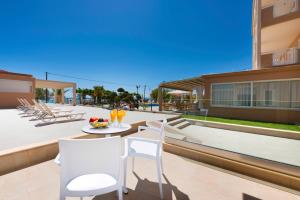a patio with chairs and a table with a bowl of fruit on it at Blue view seaside hotel in Limenaria