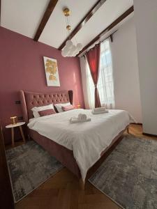a bedroom with a large bed with a pink wall at Kromatic 5 Boutique Studios - Old town Center in Braşov