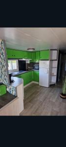 a kitchen with green cabinets and a white refrigerator at Mobilhome spacieux in Pornic