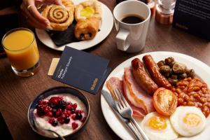 a table with two plates of breakfast foods and a cup of coffee at Thistle Trafalgar - Leicester Square in London