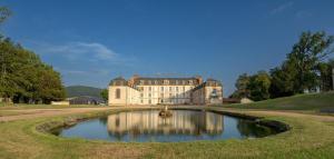 a large house with a pond in front of it at Au Petit Chateau les Bains a Thermen Morvan in Saint-Honoré-les-Bains