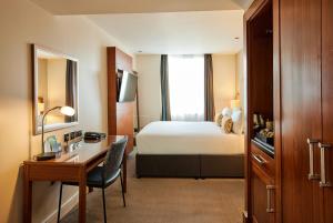a hotel room with a bed and a desk and a bedroom at Thistle Trafalgar - Leicester Square in London