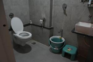 a bathroom with a toilet and a trash can at 2bhk penthouse with open tarace in Vadodara +4 photos