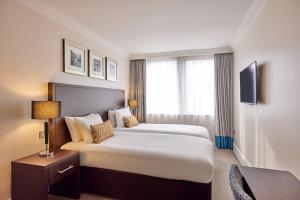 a hotel room with a large bed and a desk at Thistle Trafalgar - Leicester Square in London