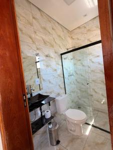 a bathroom with a toilet and a glass shower at Fonsecas House Suíte Privativas in Paraguaçu
