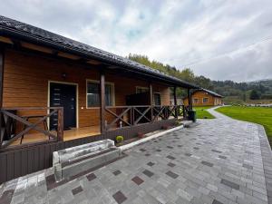 a wooden cabin with a porch and a patio at Bilia Tustani in Urych