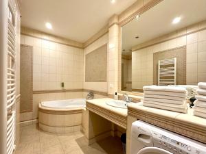 a bathroom with a tub and a sink and a washing machine at Slunecni Lazne Apartments in Karlovy Vary +82 photos