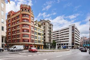 a street with cars on a city street with buildings at Plaza del Carmen in Gijón