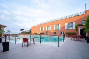a patio with a pool and chairs and a building at Hotel Punta San Martino in Arenzano