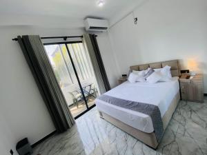 a bedroom with a large white bed and a balcony at The Galaxy Airport Hotel in Negombo