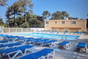 a pool with blue and white chairs and a building at Appartement Carcans Maubuisson in Carcans