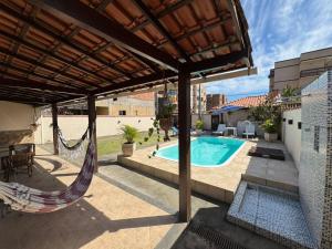 a patio with a hammock and a swimming pool at CasaPraiaSol1 in Rio das Ostras