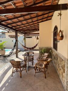 a patio with chairs and tables and a hammock at CasaPraiaSol1 in Rio das Ostras