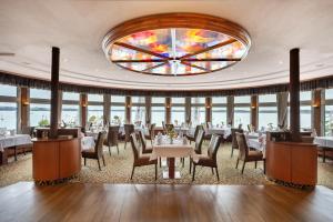 a dining room with tables and chairs and a stained glass window at Seehotel Fährhaus in Bad Zwischenahn