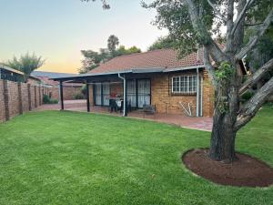 a house with a green yard with a tree at ORT Tranquil Stay in Boksburg