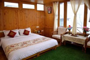 a bedroom with a bed and a chair and windows at Top Mountain Mist Near Jibhi in Banjār