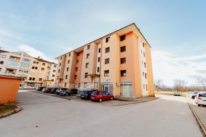 a large building with cars parked in a parking lot at Apartman Deja vu in Livno