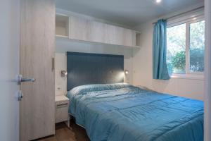 a bedroom with a blue bed and a window at Camping Village Torre Pendente in Pisa +115 photos