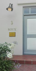 a building with a door and a sign that reads roku at 3 on Roux in Franschhoek