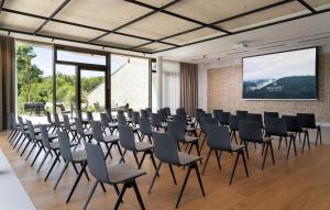 a room with a bunch of chairs and a screen at WALDWEIT Rheingau Hotel und Retreat in Kiedrich