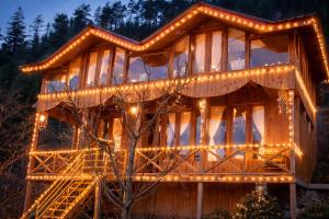 a large wooden house with lights on it at Top Mountain Mist Near Jibhi in Banjār